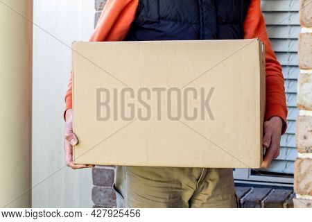 Parcel Box Delivered To A Front Door Of Residential Building By Delivery Courier Man. Online Shoppin