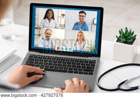 Female Therapist Video Calling Group Of Doctors Colleagues In Office