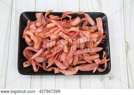 Squid (lat. Teuthida) Half-rings Cut Into Strips On A Black Rectangular Plate With A Wooden Table Ba