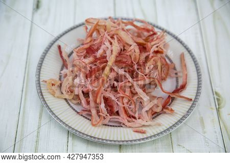 Squid Shavings (lat. Teuthida) On A Round Plate With A Wooden Table Background. Food Is A Delicacy S