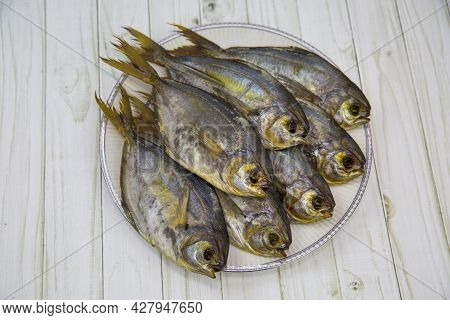 Piranha Fish (latin Pygocentrus Nattereri) Dried With A Head On A Round Plate With A Wooden Table Ba