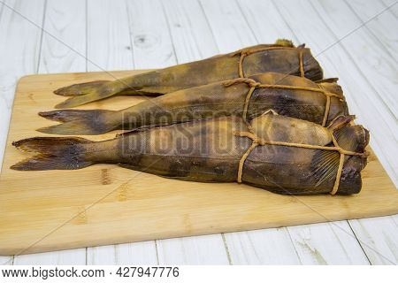 Terpug (latin: Hexagrammos Stelleri) Hot Smoked Without Heads Tied With A Rope On A Wooden Board. Fo