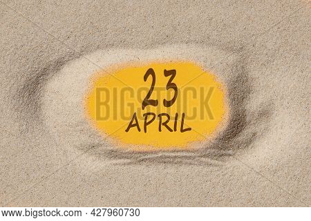 April 23. 23th Day Of The Month, Calendar Date. Hole In Sand. Yellow Background Is Visible Through H
