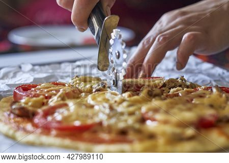 Cutting Homemade Pizza. Female Hand Slicing Freshly Baked Pizza. Close-up View Of A Hand Of Chef Bak