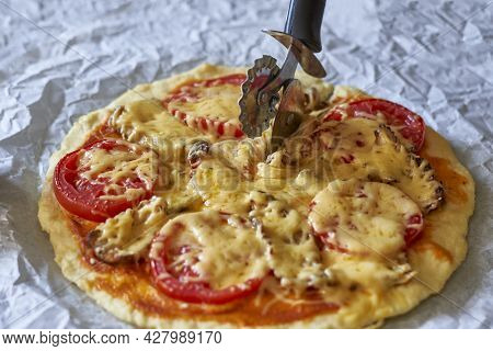Cutting Homemade Pizza. Female Hand Slicing Freshly Baked Pizza. Close-up View Of A Hand Of Chef Bak