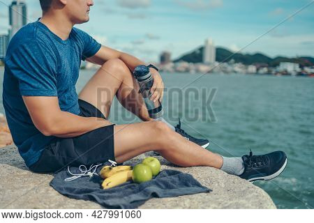 Sport Man Sitting After Running And Holding Water Bottle Drink. Sport Thirsty And Resting After Exer