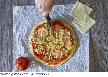 Cutting Homemade Pizza. Female Hand Slicing Freshly Baked Pizza. Close-up View Of A Hand Of Chef Bak