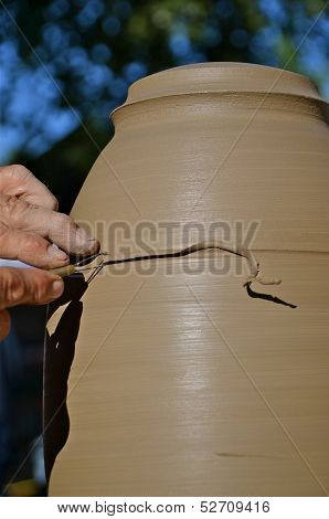 a potter is trimming a lamp as it turns on the wheel