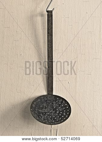 vintage skimmer ladle over old painted yellowish wall