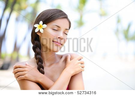 Spa wellness beach beauty woman relaxing with eyes closes on Hawaii beach. Beautiful serene and peaceful young mixed race Asian Caucasian female model on holiday travel resort. Flower in braided hair.
