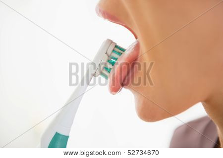 Closeup On Young Woman Cleaning Tongue Using Toothbrush
