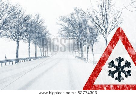 Snowfall on a country road with traffic sign