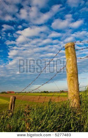 Platteland met prikkeldraad hek