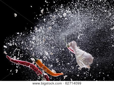 Chicken meat with flour in freeze motion, isolated on black background