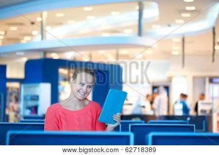 Woman sitting in a waiting room reading tablet
