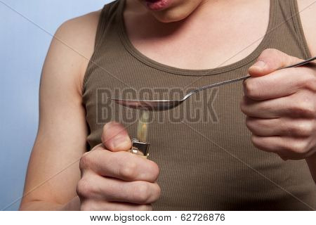 Man with a hardline drug addiction heating drugs in a spoon over a flame 