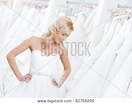 Youg girl is trying on an amasing wedding gown, white background