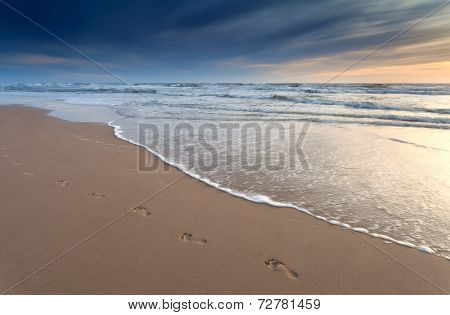 Foot Prints On Sand Beach At Sunset