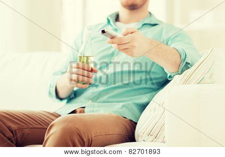 drinks, television, leisure and people concept - man changing tv channels and drinking beer at home
