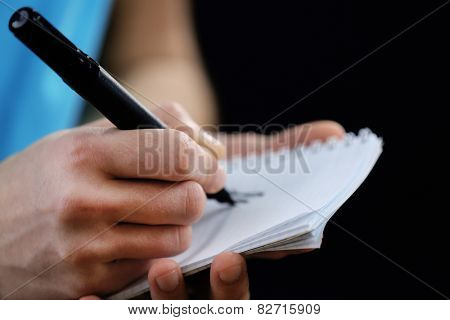 Sportsman signing autograph on small notebook on black background