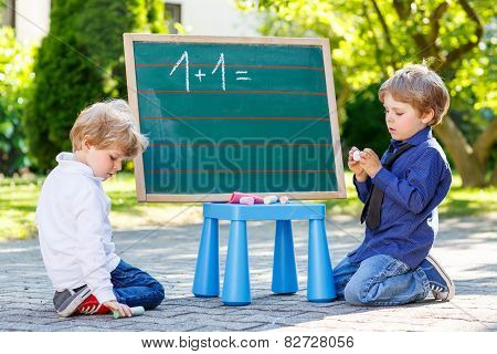 Two Siblinig Boys At Blackboard Practicing Mathematics