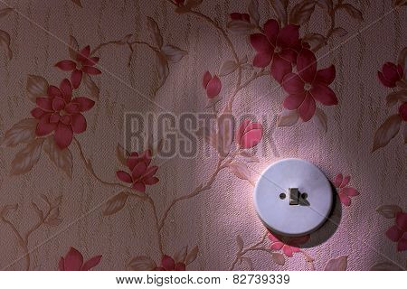 an old wallpaper with light switch. symbolic photo for renovation and remodel.
