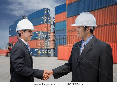 Two Of Mid Adult Businessman Shaking Hands  Near Cargo Containers