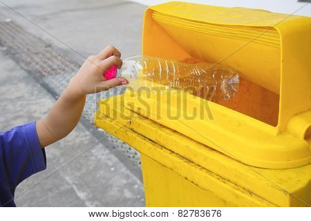 Children Hand Dropping Used Bottle In The Trash