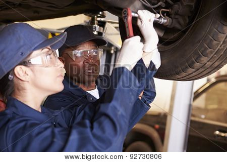 Teacher Helping Student Training To Be Car Mechanics