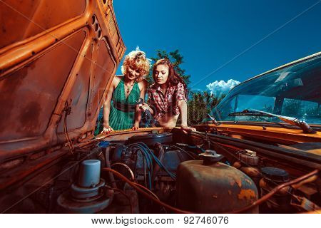 Beautiful Woman Mecanic Is Repairing A Car Another Woman Is Watching.