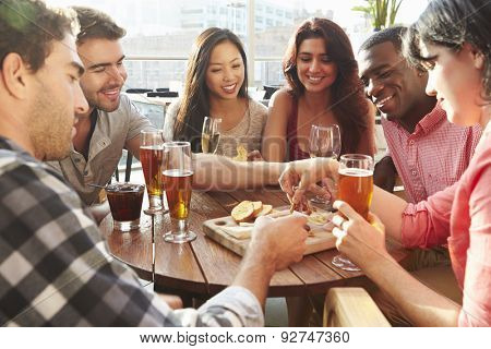 Group Of Friends Enjoying Drink And Snack In Rooftop Bar