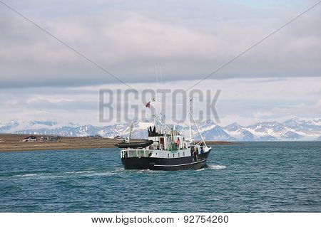 Ship sails along the shore of Longyearbyen in Longyearbyen, Norway.