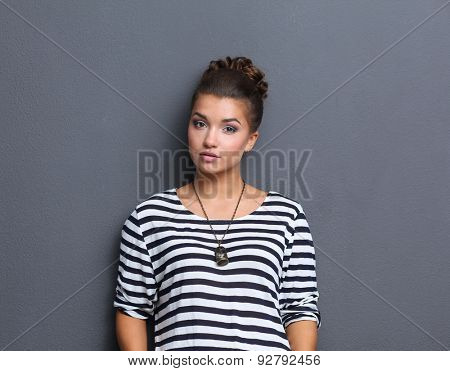 A young woman standing, isolated on graybackground