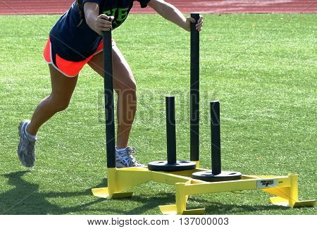 An athlete getting stronger by pushing wights on a sled