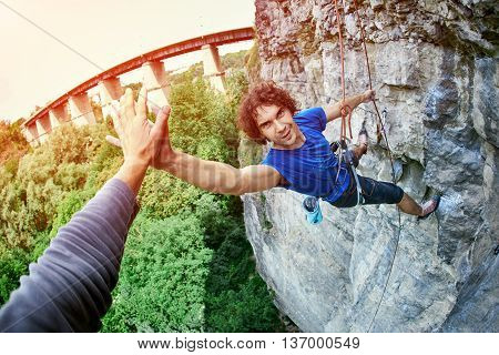 male rock climber. man climbs on a rocky wall, finished climbing and shakes hands with a friend