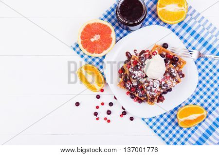 Belgian waffles with berries ice cream and chocolate sauce on a plate
