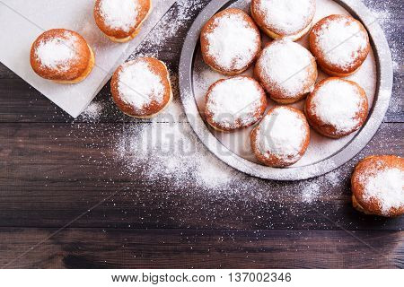 German donuts - berliner with jam and icing sugar in a tray on a wooden background. Top view