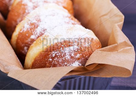 German donuts - berliner with icing sugar in a box on a dark wooden background