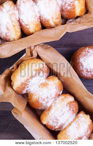 German donuts - berliner with jam and icing sugar in a box on a dark wooden table. Top view
