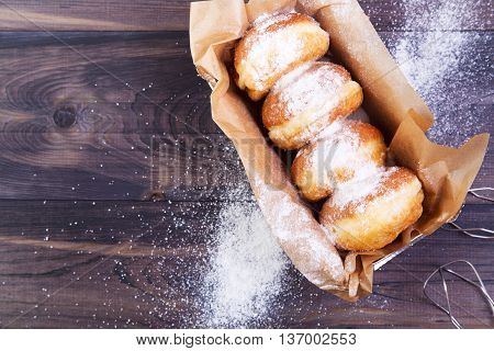German donuts - berliner with jam and icing sugar in a box on a dark wooden table. Top view with copy space