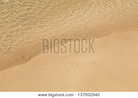 Beautiful crystal clear sea water, Gentle waves breaking on golden sand beach.  From above with copy space.