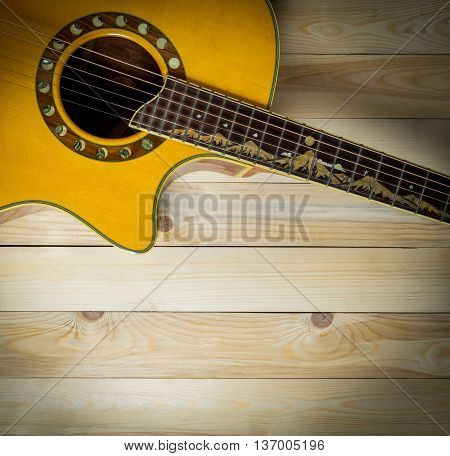 Acoustic guitar on wooden panel with copy space vignetting