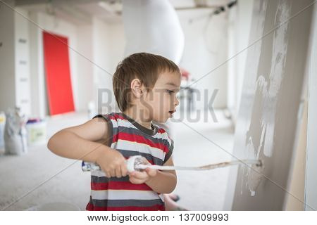 Little cute boy painting on a wall