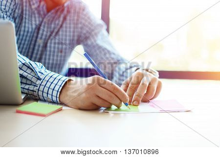 Business man working at office with laptop and documents on his desk. Analyze plans, papers, hands keyboard. Blurred background, film effect