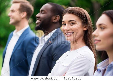 Ready to work together. Cheerful delighted beautiful woman smilin and expressing gladness while standing with her colleagues outside