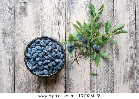 Blueberries in the metal cup on wooden background with leaves
