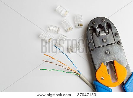 Crimper connectors and ethernet cable on white background