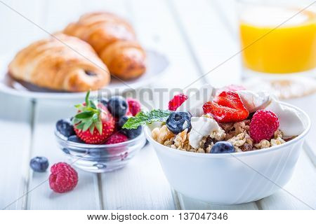 Muesli with yogurt and berries on a wooden table. Healthy fruit milk yogurth and cereal brakfast.
