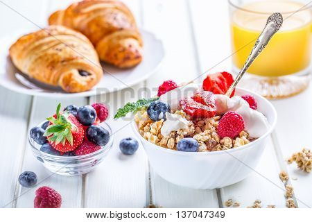 Muesli with yogurt and berries on a wooden table. Healthy fruit and cereal brakfast.