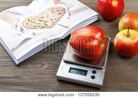 Apples with digital kitchen scales on wooden table. Cooking apple cake concept